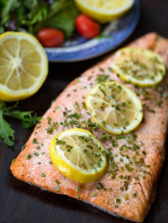 Baked Steelhead Trout Fillet with three sliced lemons sprinkled with a green herb