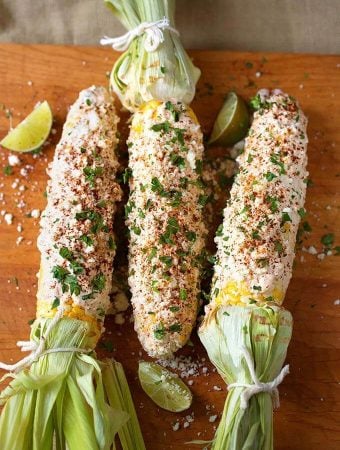 Three Mexican Street Corn (Elotes) on wooden board