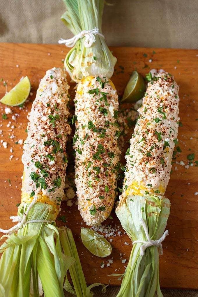 Three Mexican Street Corn (Elotes) on wooden board