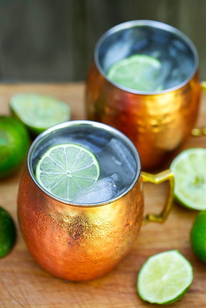 Moscow Mule Cocktail in two copper mugs with ice and sliced lime