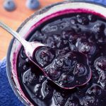Blueberry Compote being spooned out of small bowl with silver spoon