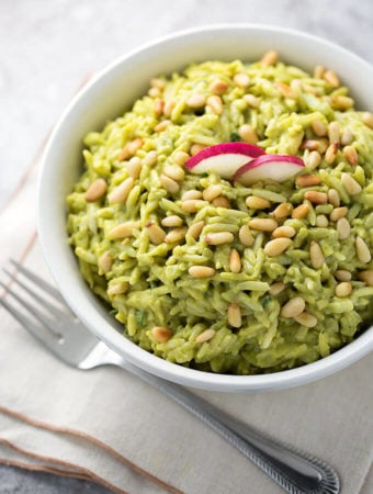 Avocado Curry Orzo Salad in a white bowl on a stack of napkins next to a fork