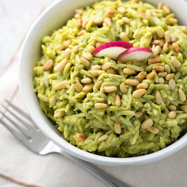 Avocado Curry Orzo Salad in a white bowl on a stack of napkins next to a fork