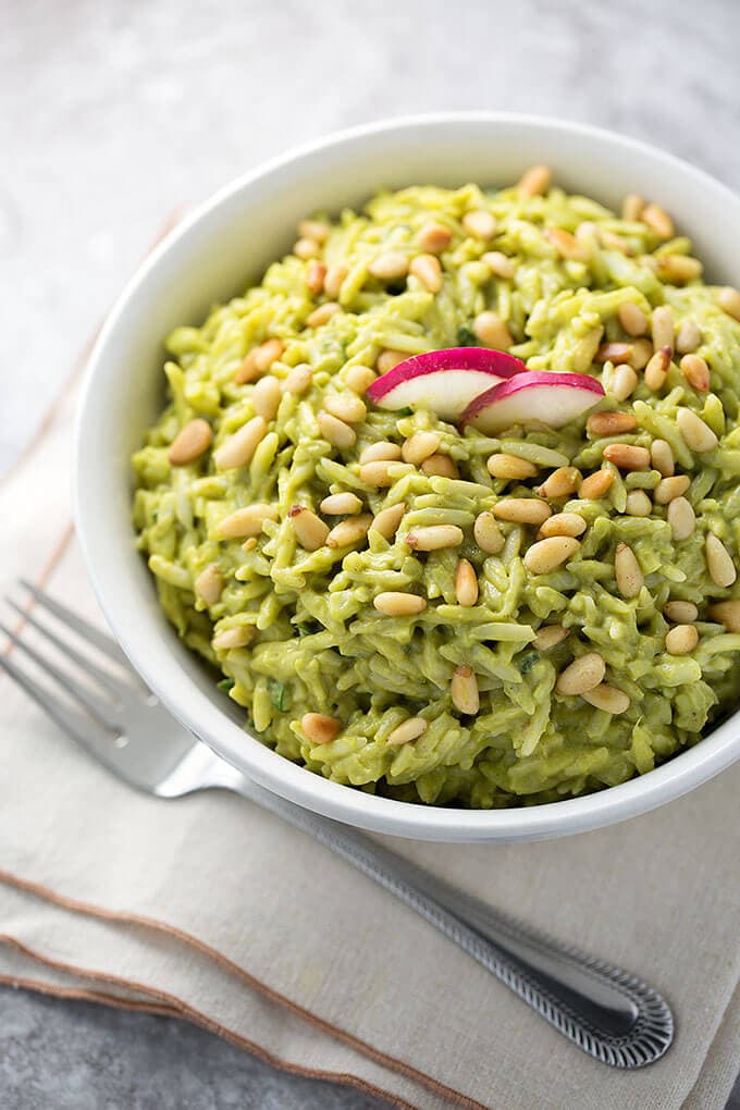 Avocado Curry Orzo Salad in a white bowl on a stack of napkins next to a fork