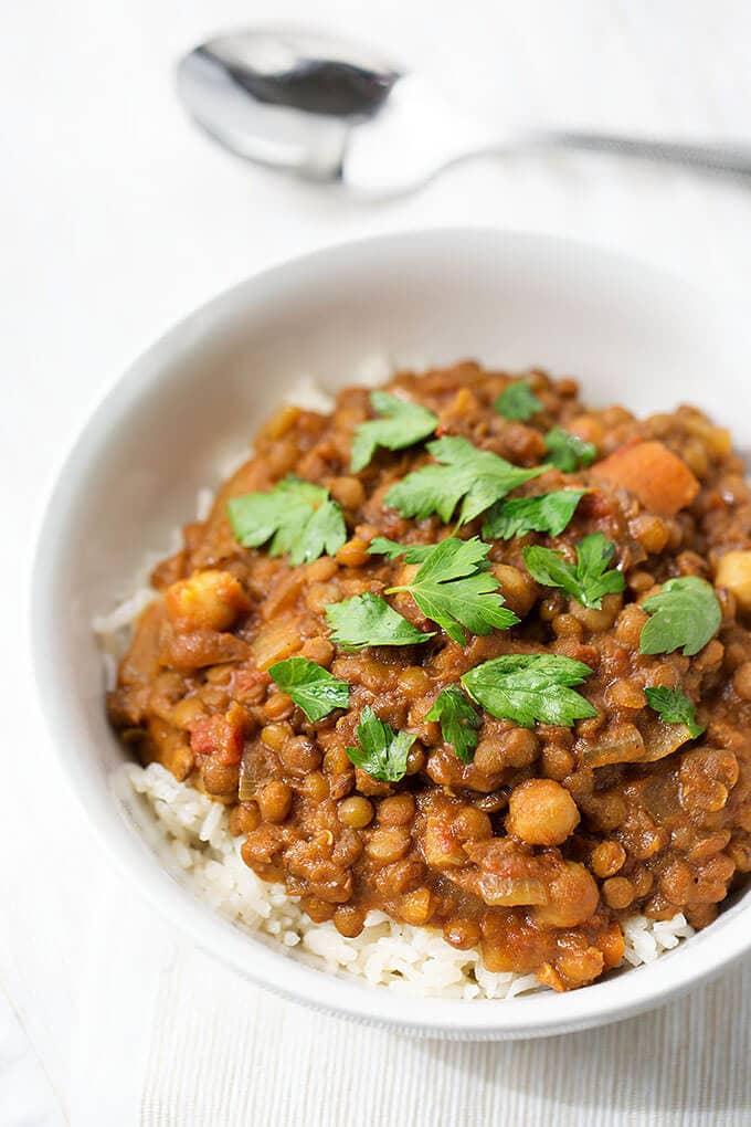 Crock Pot Curry Lentils over rice in a small white bowl