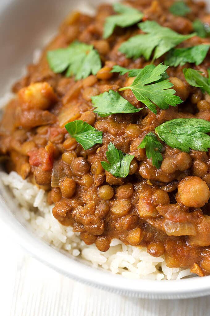 Close up of Crock Pot Curry Lentils over rice in a small white bowl