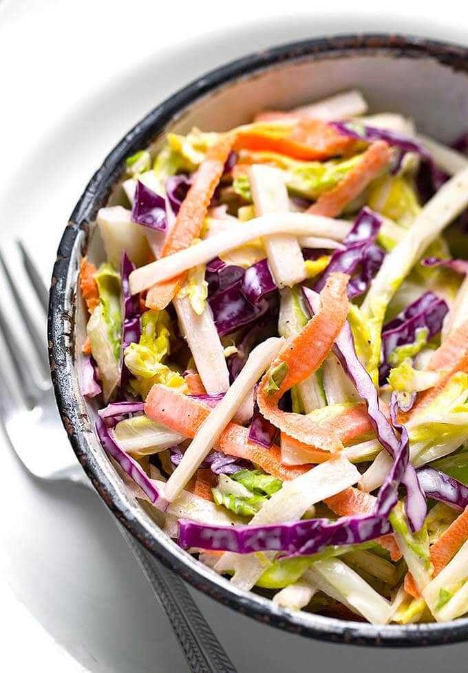  Creamy Coleslaw in a bowl on a plate with silver fork