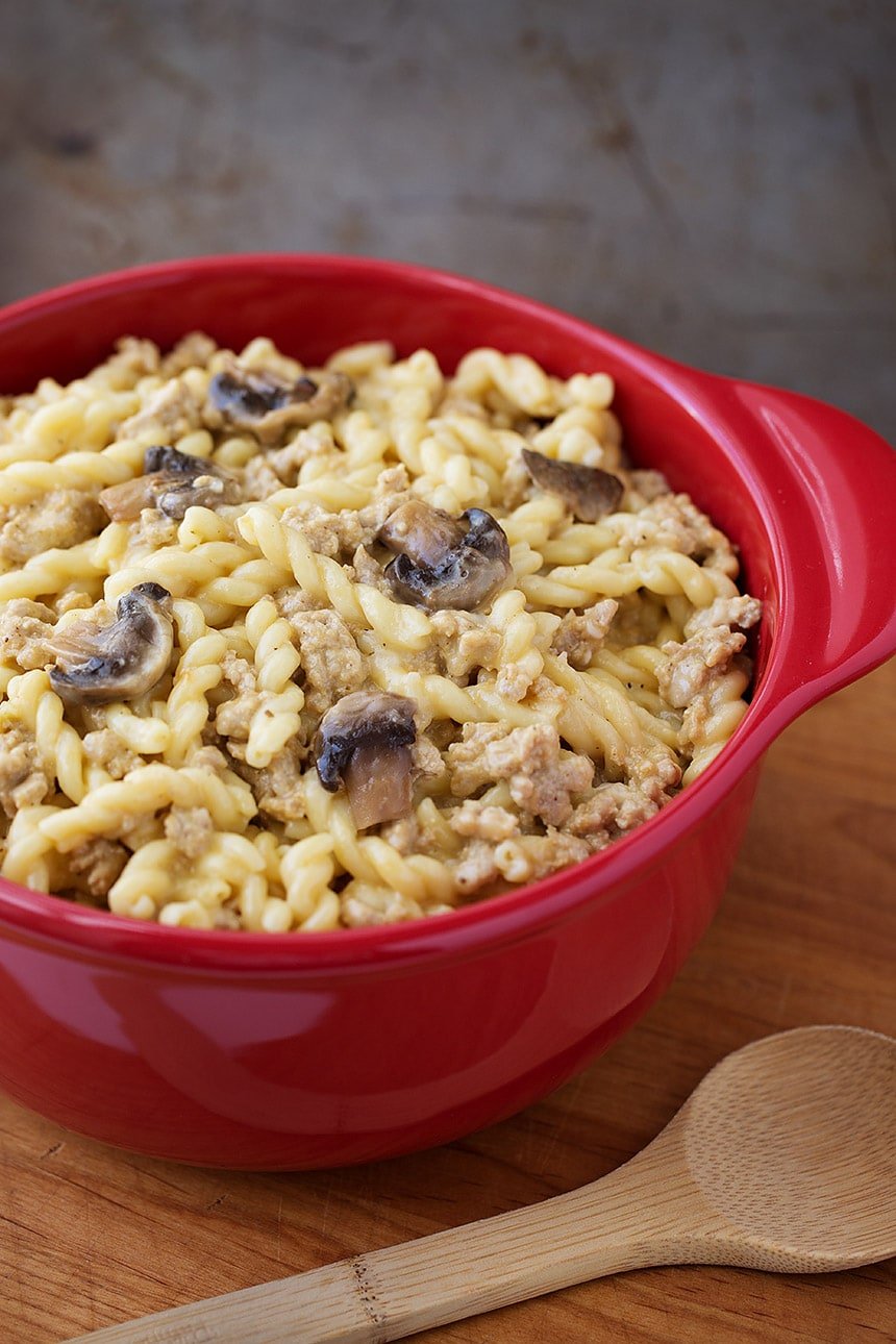 Instant Pot Cheeseburger Pasta in a red bowl on a wooden board with wooden serving spoon