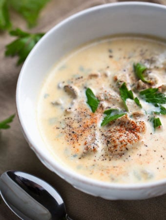 Pacific Oyster Stew in white bowl on wooden board with silver spoon