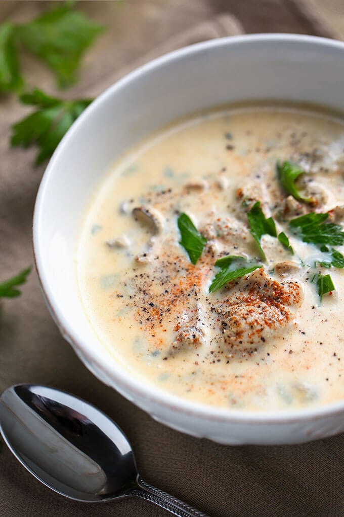 Pacific Oyster Stew in white bowl on wooden board with silver spoon