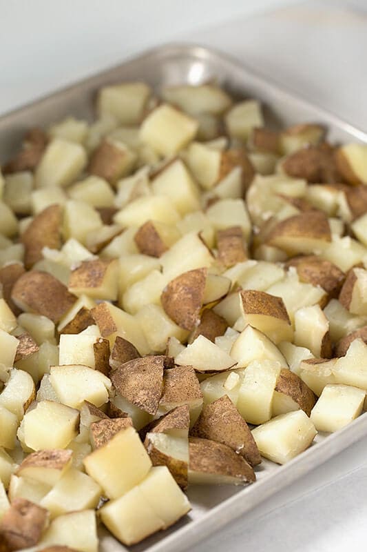 Cooked dice potatoes in metal baking sheet