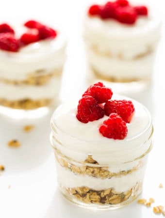 Three Vanilla Yogurt Parfaits in small glass jars on white background