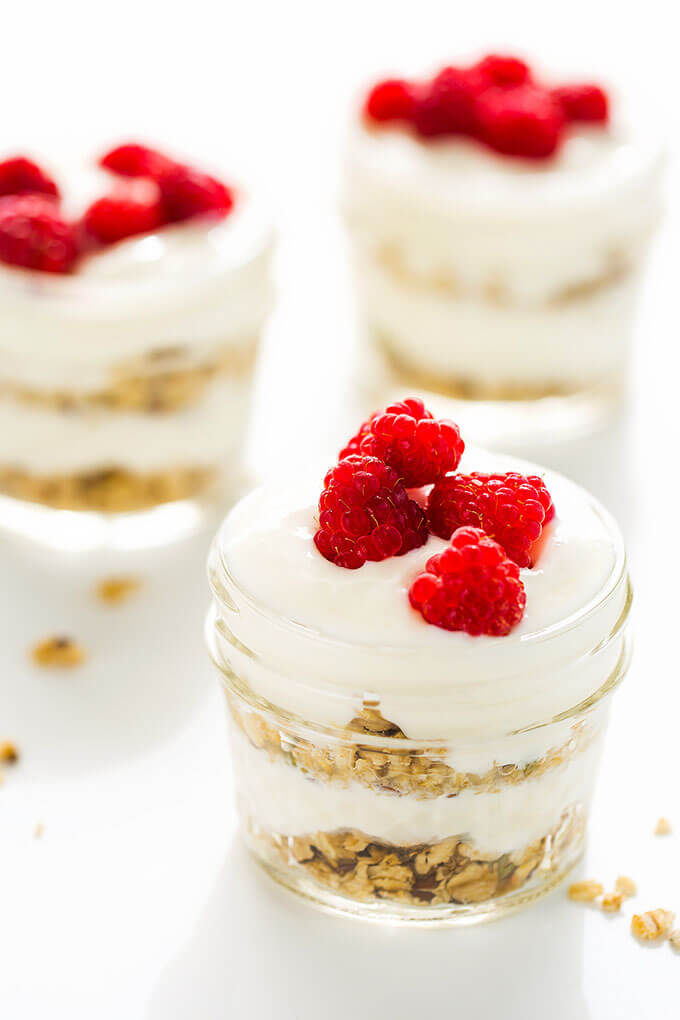 Three Vanilla Yogurt Parfaits in small glass jars on white background