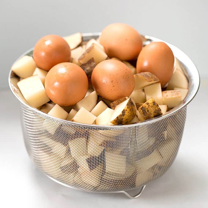 mesh basket of diced potatoes and five brown eggs