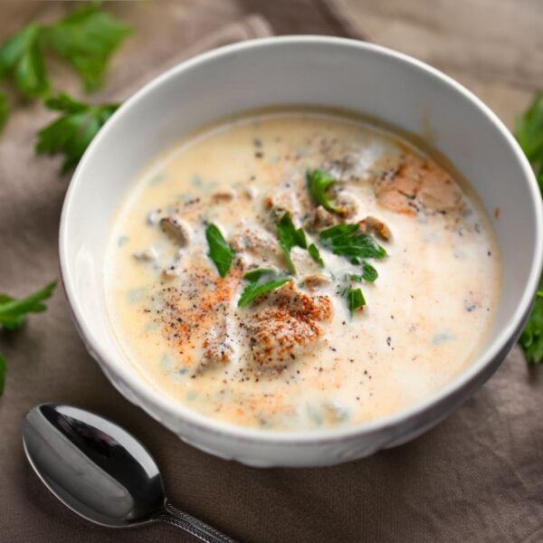 Pacific Oyster Stew in white bowl on wooden board with silver spoon