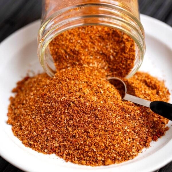 Ribs spice rub spilling from a glass jar with a measuring spoon