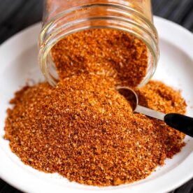 Ribs spice rub spilling from a glass jar with a measuring spoon