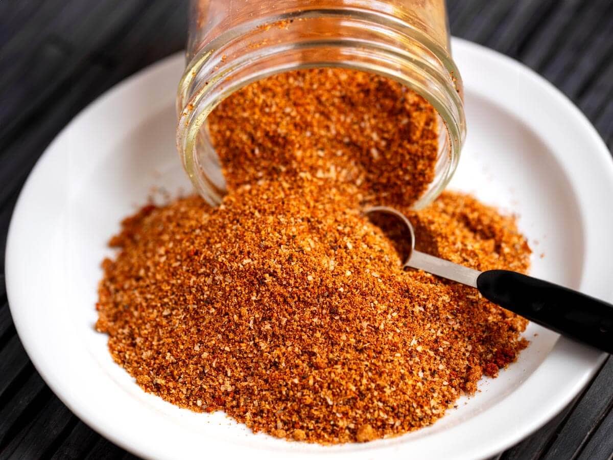 Ribs spice rub spilling from a glass jar with a measuring spoon