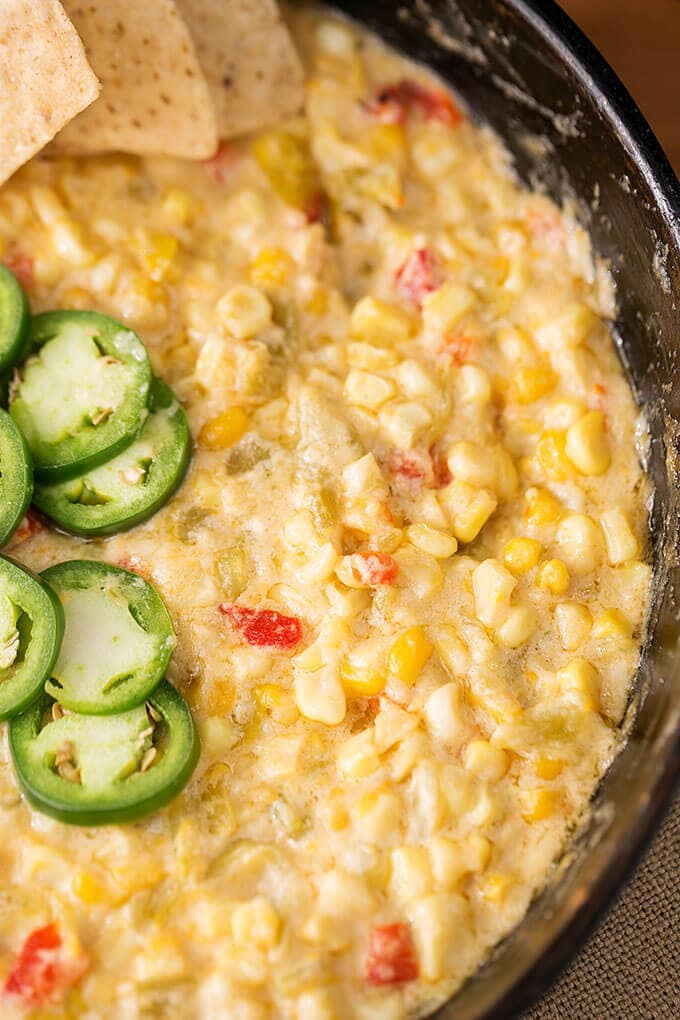 Close up of Hot Cheesy Corn Dip in a cast iron skillet topped with jalapenos 