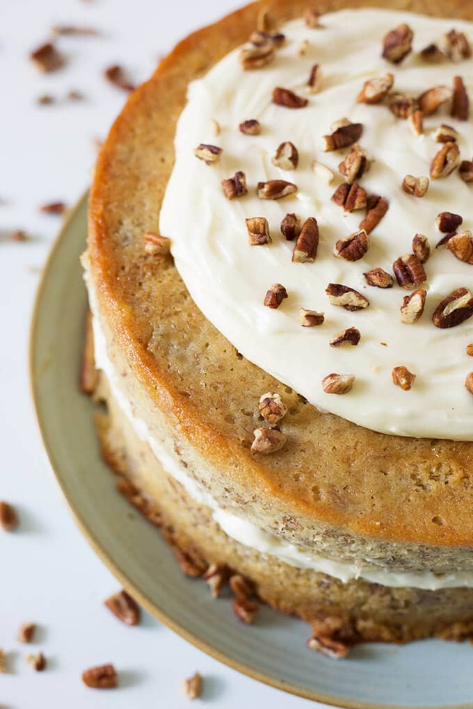  Banana Cake on light blue plate topped with frosting and pecans