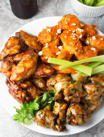 Three types of pressure cooker wings on white plate with celery