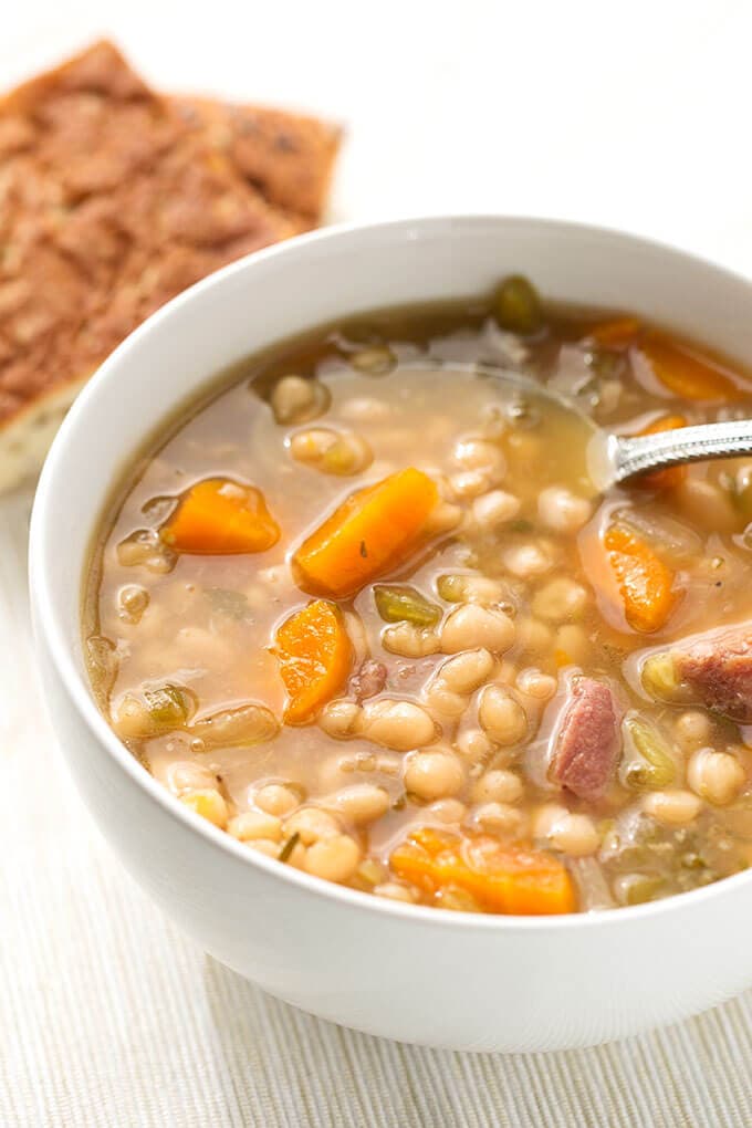 Instant Pot Ham Hock and Bean Soup in a white bowl with spoon on light background