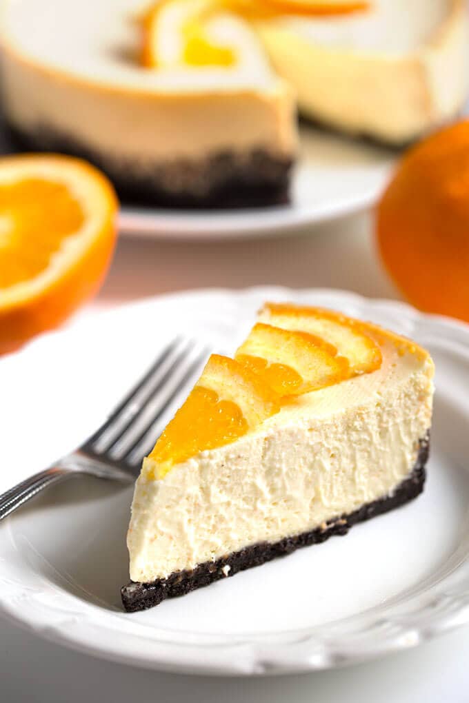 Slice of Dreamy Orange Cheesecake on white plate with fork