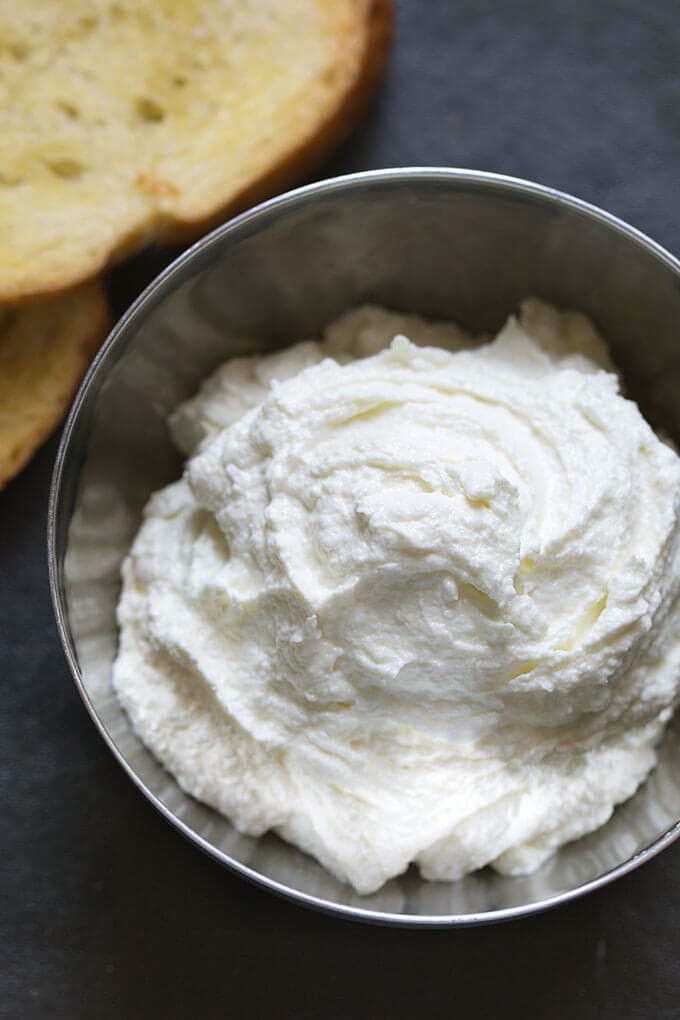 Whipped Feta Spread in small metal bowl with toasted bread in the background