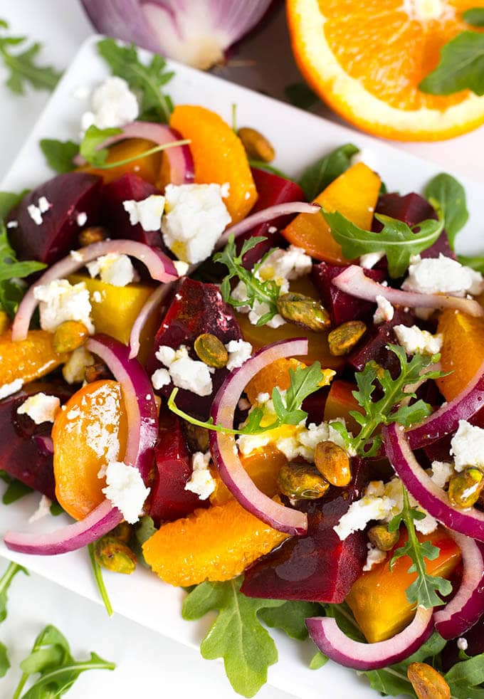 Close up of Beet Salad with Goat Cheese and Orange Vinaigrette on white rectangular plate