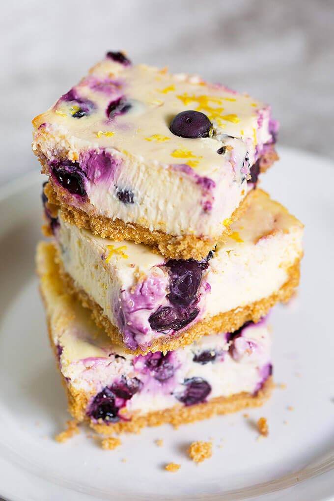 Three Blueberry Lemon Cheesecake Squares stacked on top of each other on a white plate