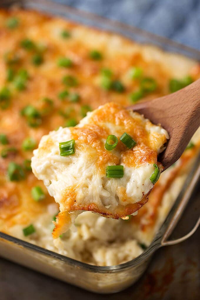 Cheesy Baked Orzo in a glass casserole dish being served with wooden spoon