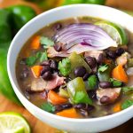 Hatch Green Chile Black Bean Soup in a white bowl on a wooden board