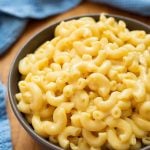 Mac and Cheese in a brown bowl on a wooden board and blue napkin