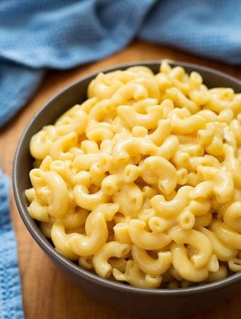 Mac and Cheese in a brown bowl on a wooden board and blue napkin