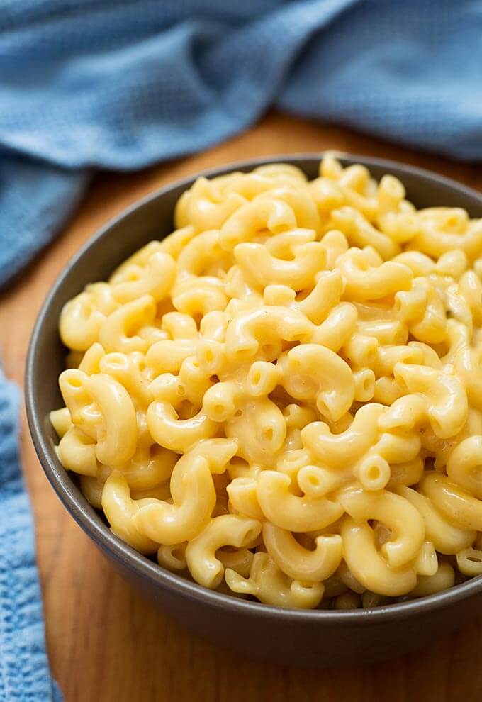 Mac and Cheese in a brown bowl on a wooden board and blue napkin