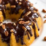 Instant Pot Pecan Chocolate Chip Cake bunt pan shaped topped with pecans and chocolate syrup on white plate