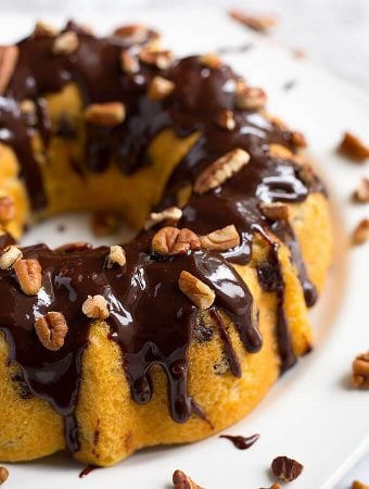 Instant Pot Pecan Chocolate Chip Cake bunt pan shaped topped with pecans and chocolate syrup on white plate