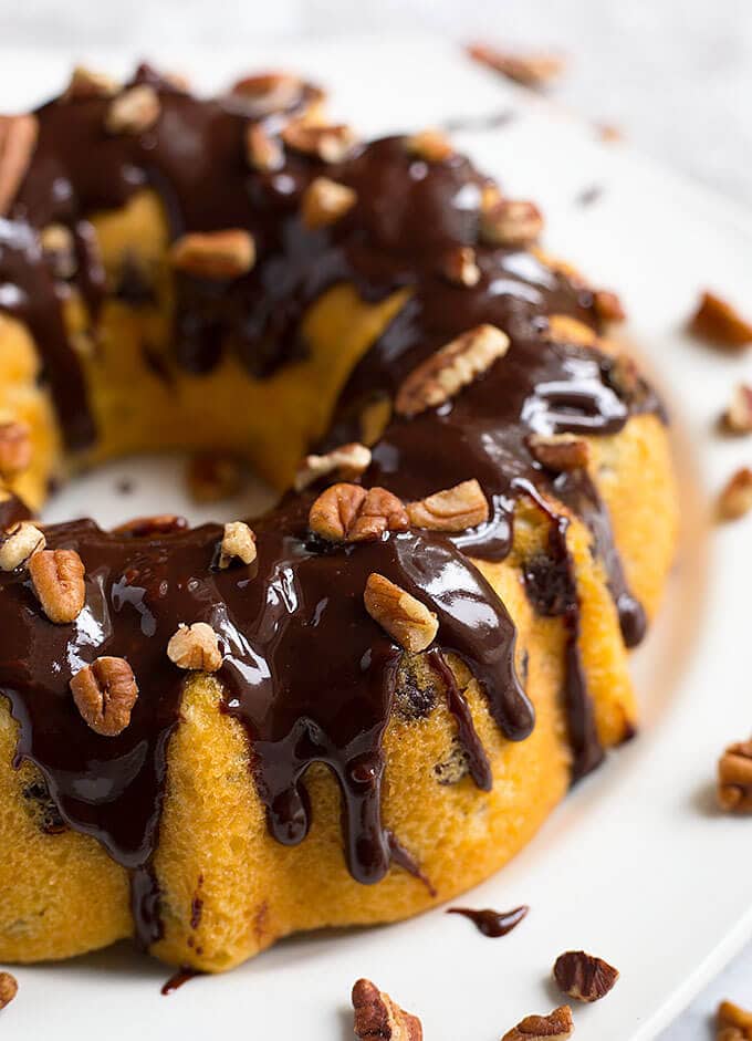 Instant Pot Pecan Chocolate Chip Cake bunt pan shaped topped with pecans and chocolate syrup on white plate