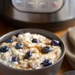 Steel Cut Oats in a dark grey bowl topped with blueberries with a pressure cooker in the background