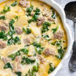 Instant Pot Zuppa Toscana (Sausage and Potato Soup) in a white bowl with scalloped edge next to silver spoon