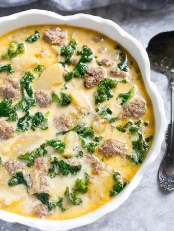 Instant Pot Zuppa Toscana (Sausage and Potato Soup) in a white bowl with scalloped edge next to silver spoon