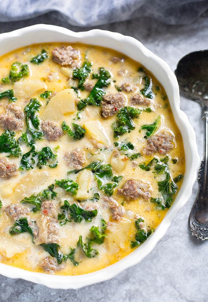 Instant Pot Zuppa Toscana (Sausage and Potato Soup) in a white bowl with scalloped edge next to silver spoon