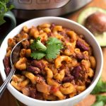 Chili Mac in a white bowl with spoon on wooden board