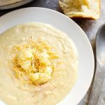 Smoky Creamy Cauliflower Soup in a white bowl next to spoon and roll