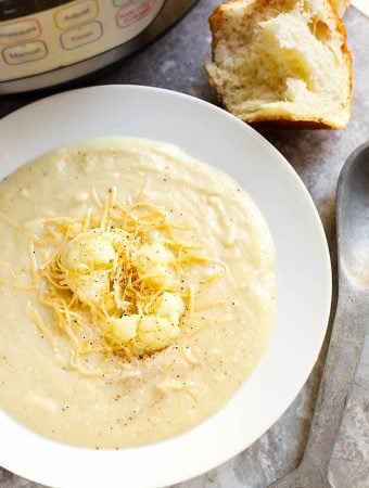 Smoky Creamy Cauliflower Soup in a white bowl next to spoon and roll