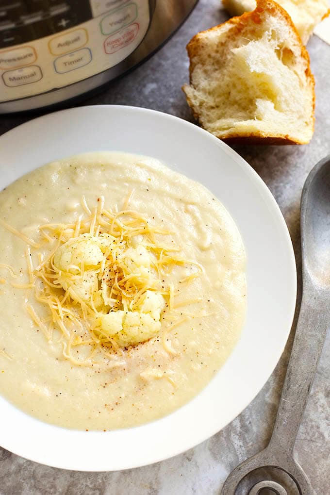 Smoky Creamy Cauliflower Soup in a white bowl next to spoon and roll