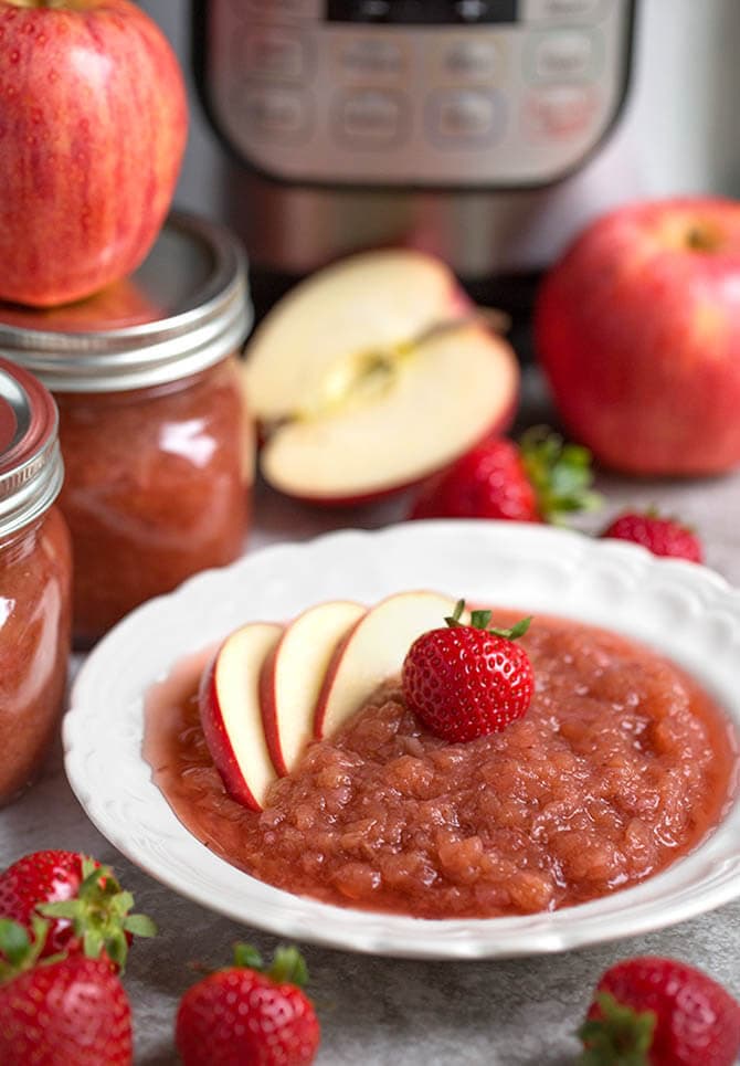 Strawberry apple sauce in a white bowl topped with sliced apples and a strawberry