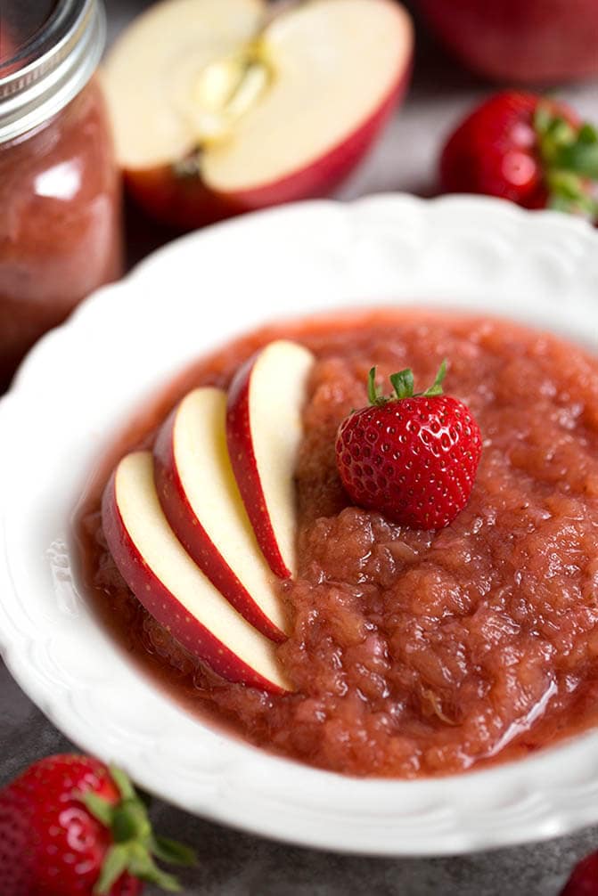 Strawberry apple sauce in a white bowl topped with sliced apples and a strawberry