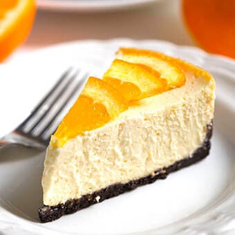 Slice of Dreamy Orange-Cheesecake on white plate with fork