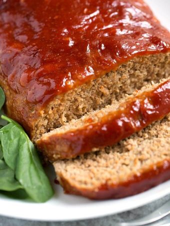 Tasty Turkey Meatloaf on white plate next to baby spinach
